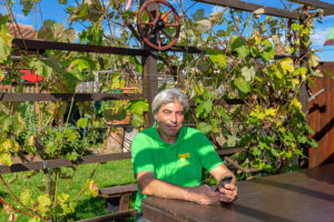 Salvatore in seinem Garten im Areal Buen am 6. Oktober 2018. Das Rad im Hintergrund ist ein Erinnerungs-Geschenk von den Pächtern Inge und Edi an Salvatore, als sie in Rente gingen. Der Holztisch ist ein Geschenk vom Pächter Egidio weil er sich einen neuen kaufte. Die Weintrauben im Hintergrund züchtet Salvatore zum Essen.