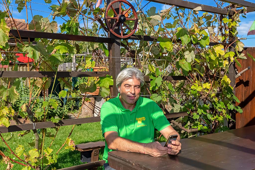 Salvatore in seinem Garten im Areal Buen am 6. Oktober 2018. Das Rad im Hintergrund ist ein Erinnerungs-Geschenk von den Pächtern Inge und Edi an Salvatore, als sie in Rente gingen. Der Holztisch ist ein Geschenk vom Pächter Egidio weil er sich einen neuen kaufte. Die Weintrauben im Hintergrund züchtet Salvatore zum Essen.