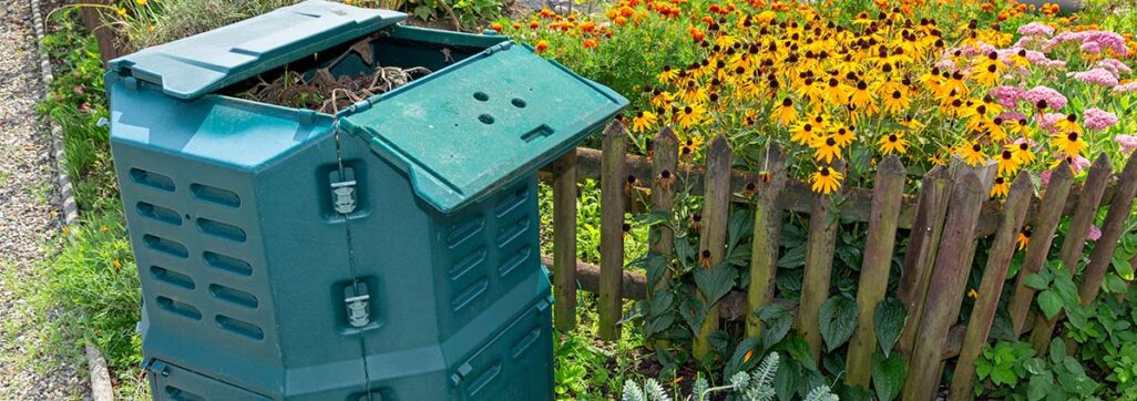 Kompostieren easy: Ein geöffneter Thermo-Komposter vor prächtig blühenden Blumen im Familiengarten Areal Buen, Ende Sommer, sozusagen eine Gratis-Kompostabgabe